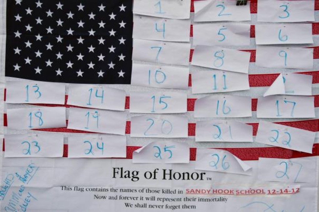 A flag hanging in Newtown's business area awaits the names of the 20 small children and six adults slaughtered by Adam Lanza. Residents have been left reeling in horror. Photo: AFP