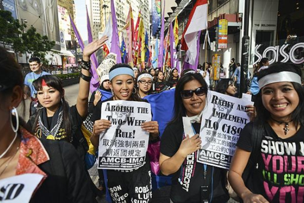 Migrant workers from Southeast Asia hold placards as they attend a workers rights rally on Sunday. Photo: AFP