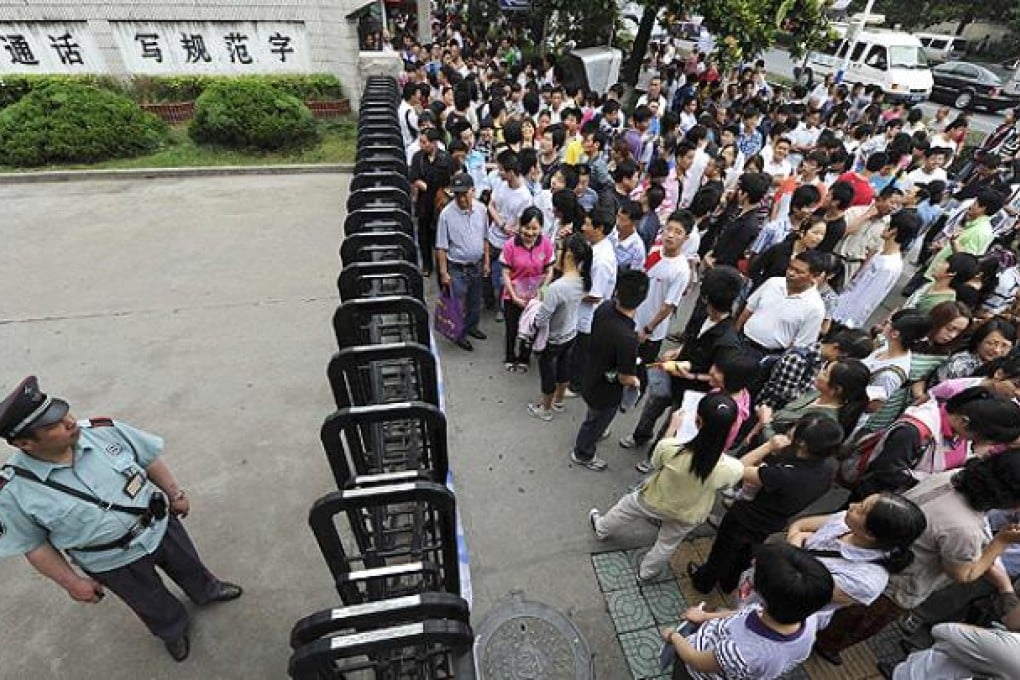 A security officer stands guard as students and their parents wait outside a school gate before the National College Entrance Exams in Hefei, Anhui province, last year. Photo: Reuters