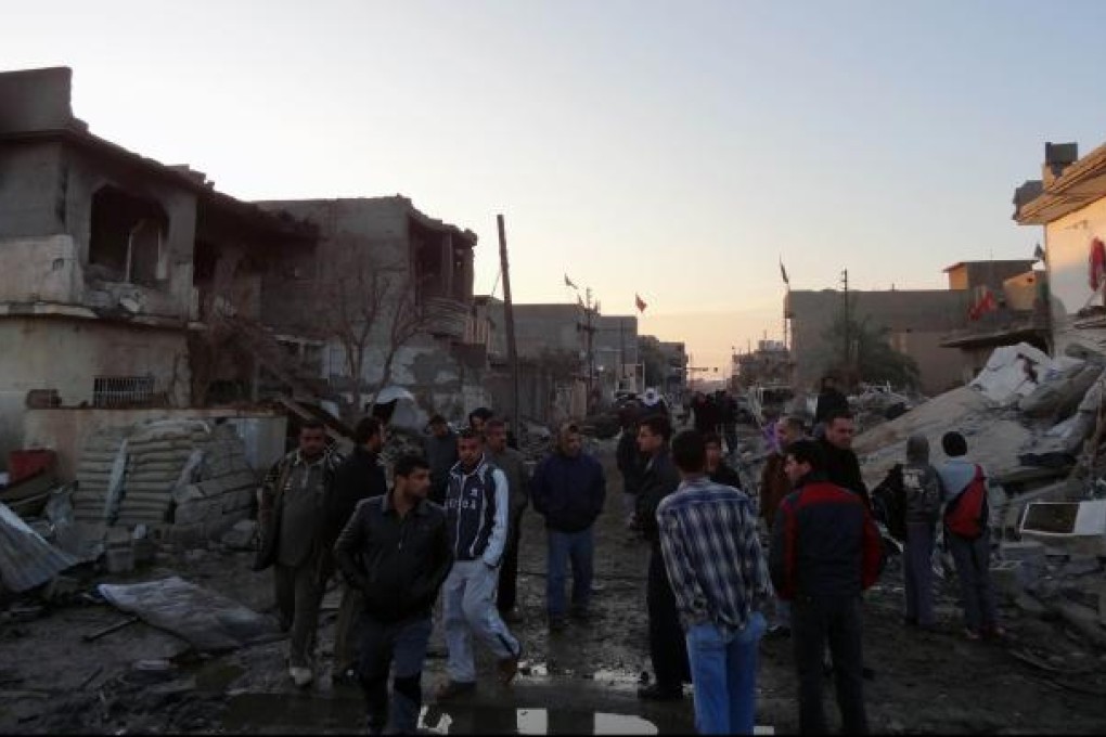Iraqis inspect the damage following two bomb blasts near a Shiite place of worship on December 17, 2012.