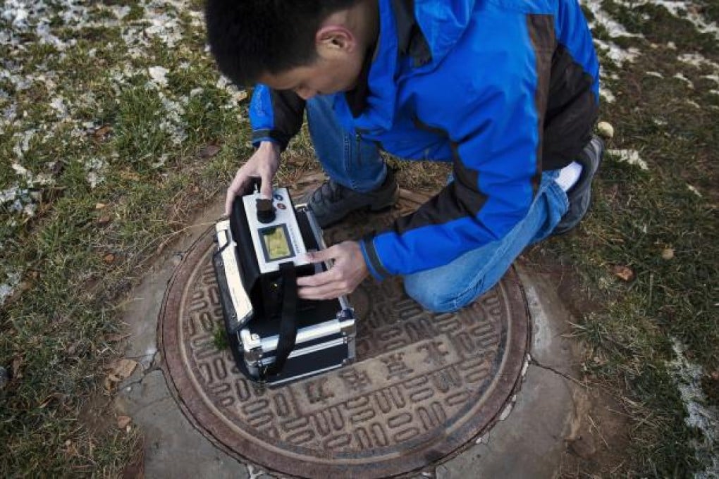 Beijing resident Tan Liang takes readings of microscopic air pollutants on a PM2.5 detector outside his residential compound in the capital. PM2.5 is causing thousands of deaths on the mainland. Photo: AP