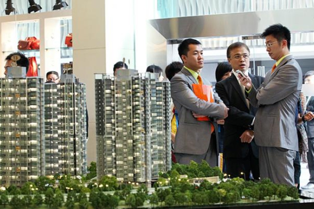 Sales representatives for a residential housing project wait for clients. Nora Tam