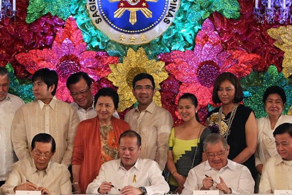 Philippine President Beningno Aquino (second left, front), senate president Juan Ponce Enrile (left, front) and speaker of the House Feliciano Belmote (second right, front) sign the 'sin tax law' as other legislators look on in Manila. Photo: AFP