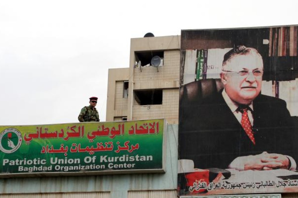 An Iraqi soldier stands guard next to a picture of Iraqi President Jalal Talabani. Photo: AFP