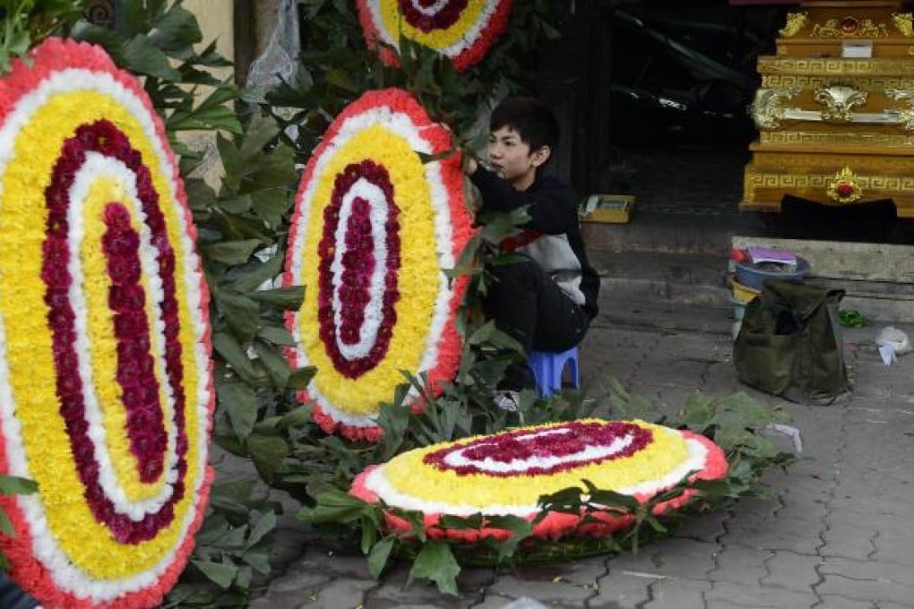 An employee prepares a funeral wreath for a customer at a funeral supplies shop which also sells coffins in Hanoi. Photo: AFP