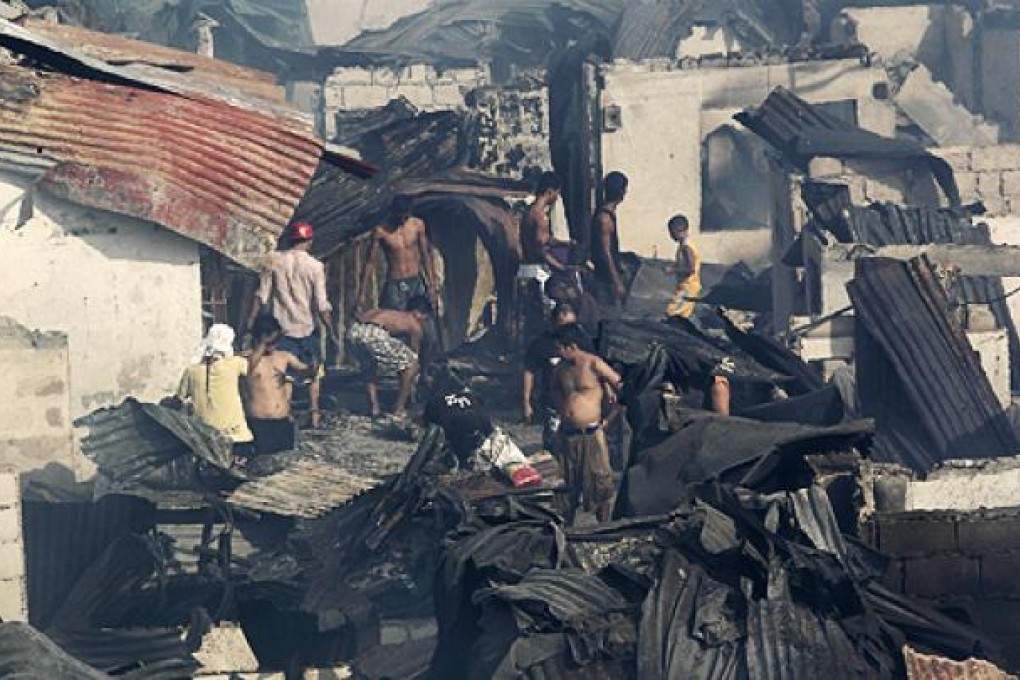 Residents return to their charred homes after fire razed some 500 houses in Manila. Photo: Reuters