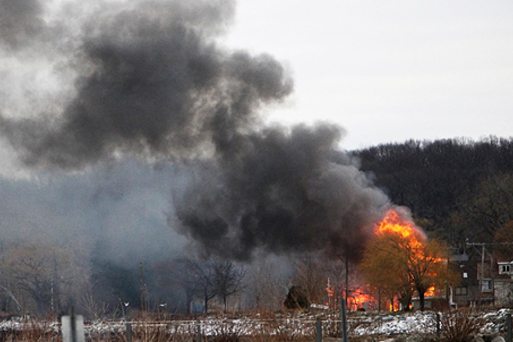 Homes burn on Lake Road where two firefighters were killed by a gunman in Webster, New York. Photo: Reuters