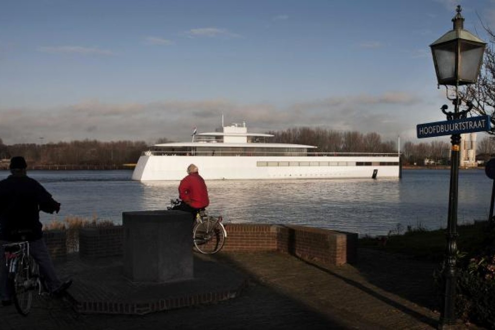 Two men on bicycles watch the yacht of late Apple co-founder Steve Jobs, the ‘Venus’, made by Dutch shipbuilder Royal de Vries in Aalsmeer, departing for a trial run. Photo: EPA
