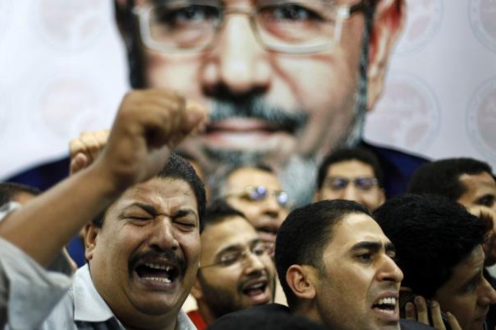 Supporters of the Muslim Brotherhood's president Mohammed Mursi celebrate in front of his picture. Photo: Reuters