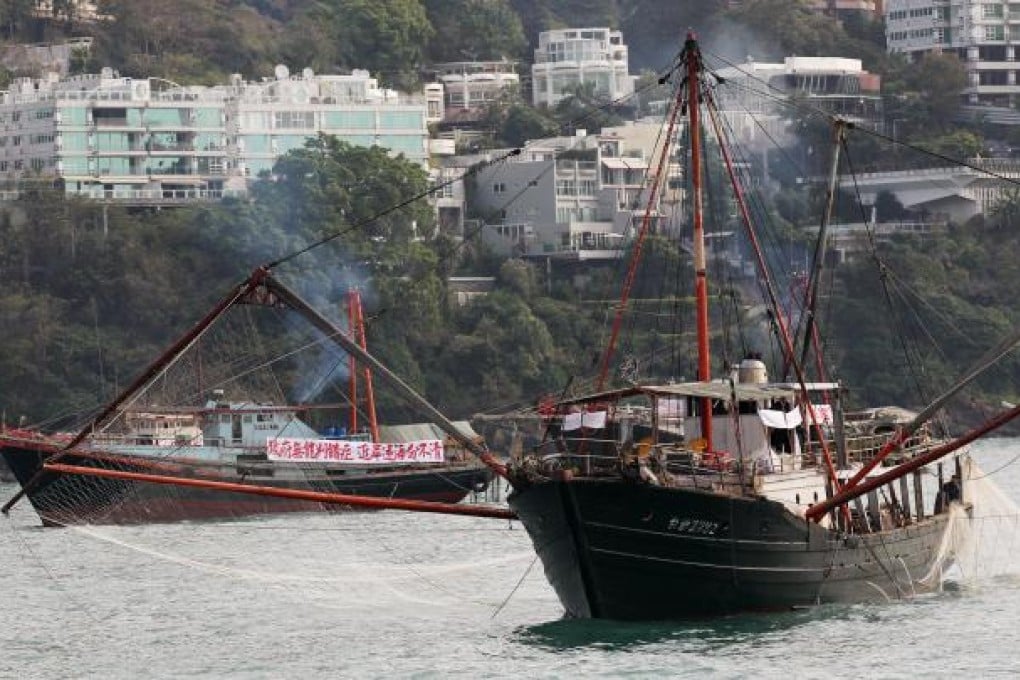 Trawler fishermen hoist their messages in Victoria Harbour yesterday, demanding adequate compensation. The protest started at Cyberport and ended in Central. Photo: Nora Tam