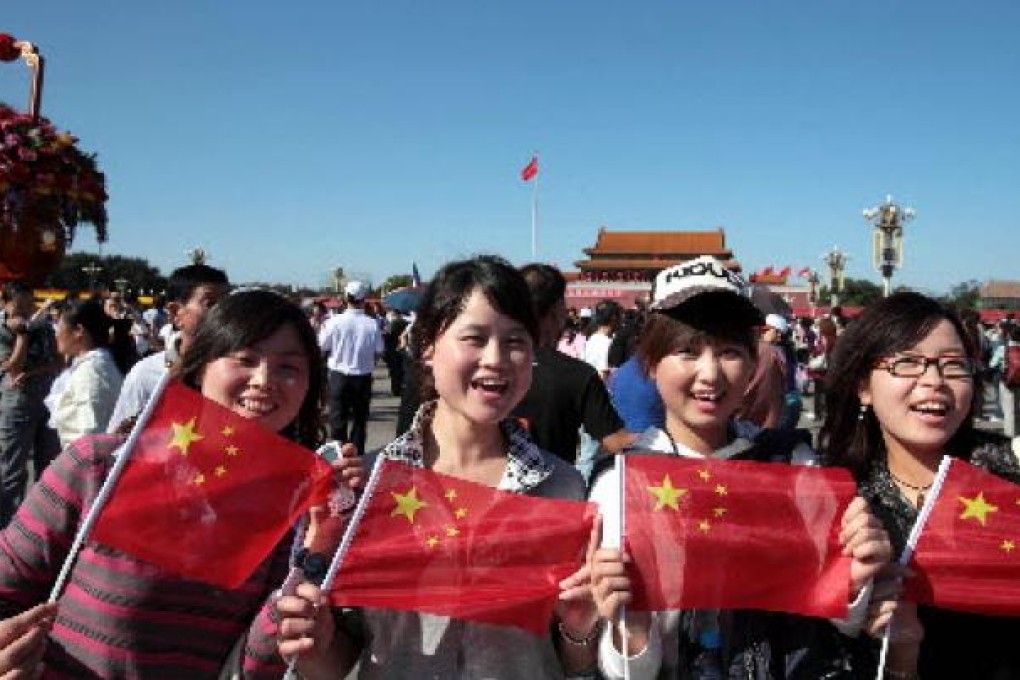 Visitors with the national flags in hands pose for photos on the Tian'anmen Square. Photo:Xinhua