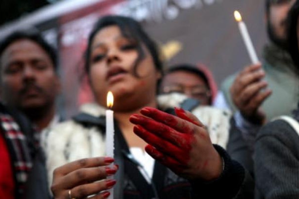 An Indian protester, with hands colored in fake blood, holds a candle during a protest campaign. Photo: EPA