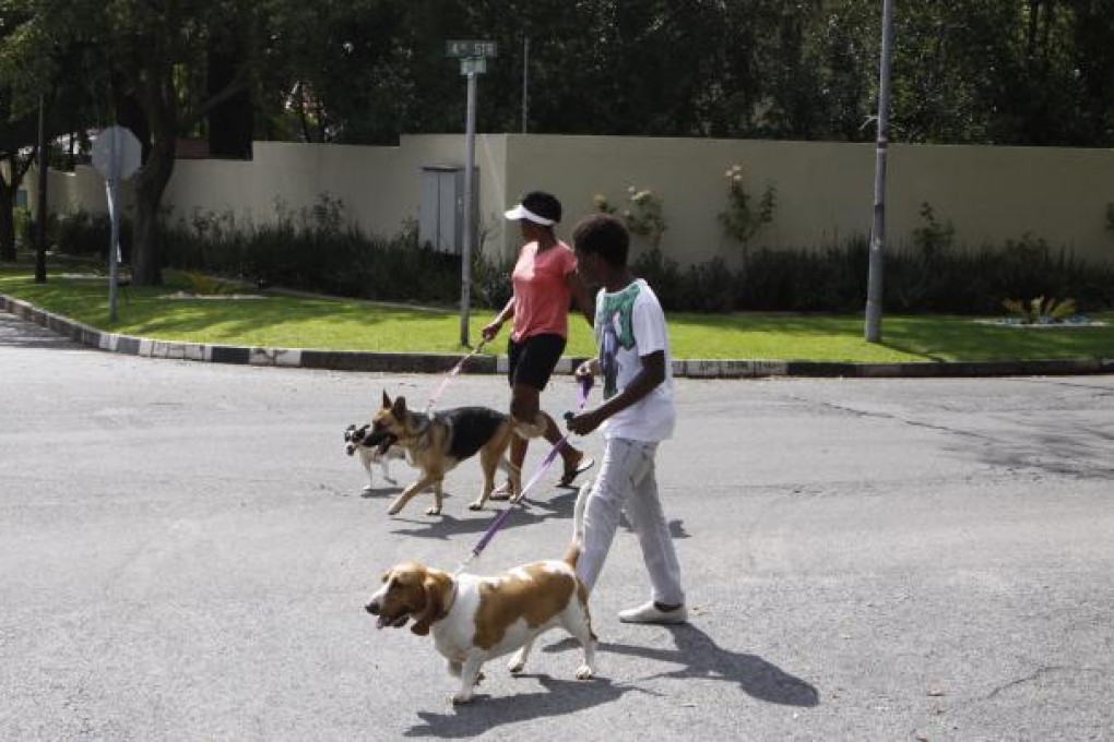 People walk their dogs outside the home of former president Nelson Mandela in Johannesburg. President Jacob Zuma made critical remarks about pet care that touch on sensitive race relations in South Africa. Photo: AP