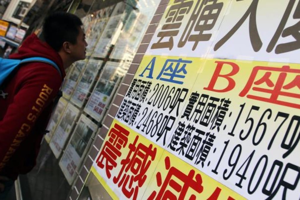 A passer-by examines new property information displayed in an estate agency's window in Happy Valley. Photo: Nora Tam