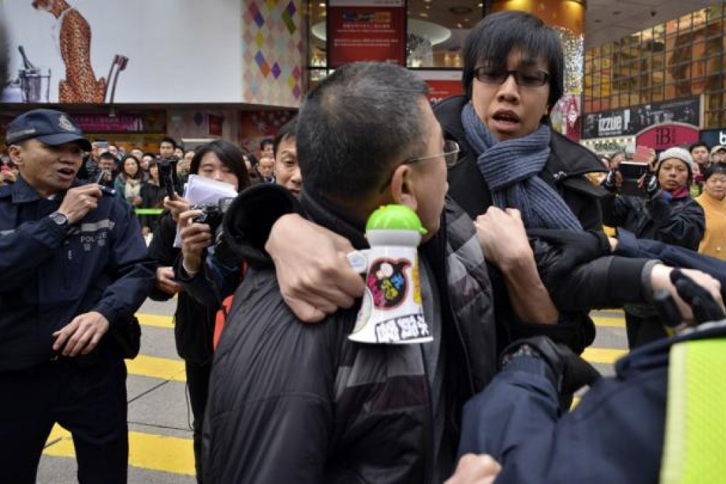 A "Leung rally" activist (centre) scuffles with a person (right) who was holding up Hong Kong's former colonial navy blue flag as marchers referring to themselves as supporters of Hong Kong and of the city's leader, Leung Chun-ying, walk though the streets. Photo: AFP