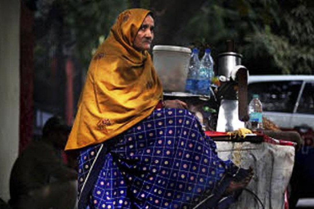 A poor elderly woman vendor sits on her cart as she waits for customers in New Delhi. India will pay billions of dollars in social welfare money directly to its poo. Photo: AP