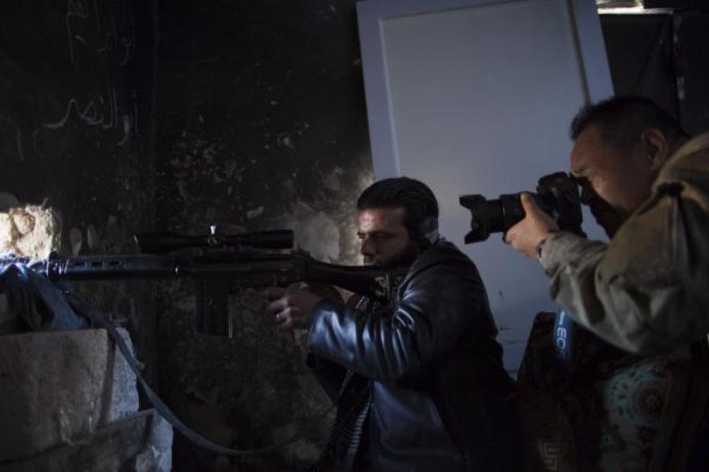 Toshifumi Fujimoto takes photos of a rebel soldier firing on government positions in the northern city of Aleppo. Photo: AFP