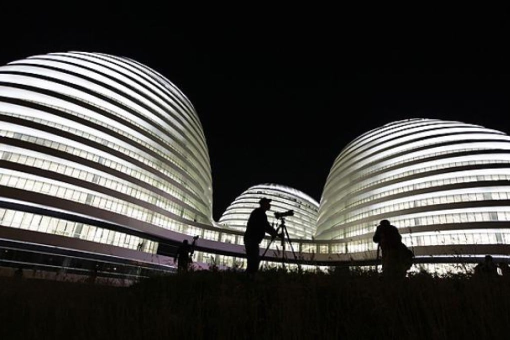A visitor prepares to take a picture of the newly opened Galaxy Soho building, designed by Iraqi-British architect Zaha Hadid, in Beijing. Photo: Reuters