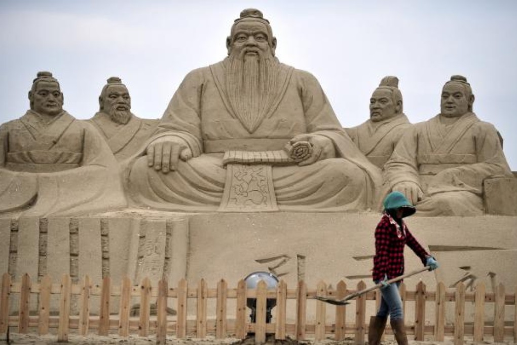A woman shovels near sand sculptures of Confucius, centre, a famed thinker and philosopher in Chinese history, in Fujian province. Photo: AP