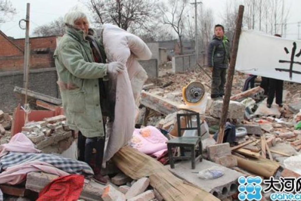 Li Guirong salvages for quilts to keep warm and other belongings amidst the rubble that was once her home. Photo: SCMP Pictures/Dahe News
