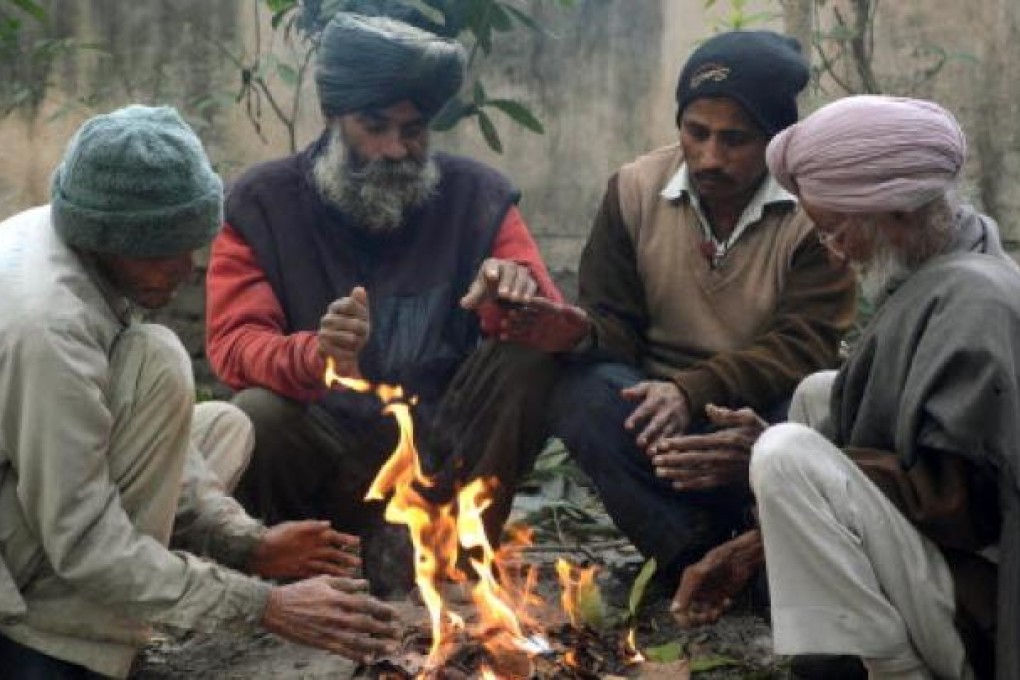 Indian workers warm themselves around a bonfire in Amritsar on Friday. New Delhi has suffered its coldest day in 44 years amid a cold snap across northern India. Photo: AFP