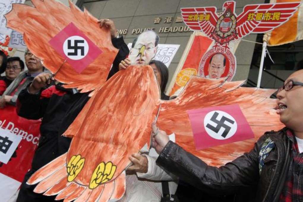Protesters brandish paper falcon and mask of police commissioner Andy Tsang at police headquarters in Wan Chai. Photo: Felix Wong