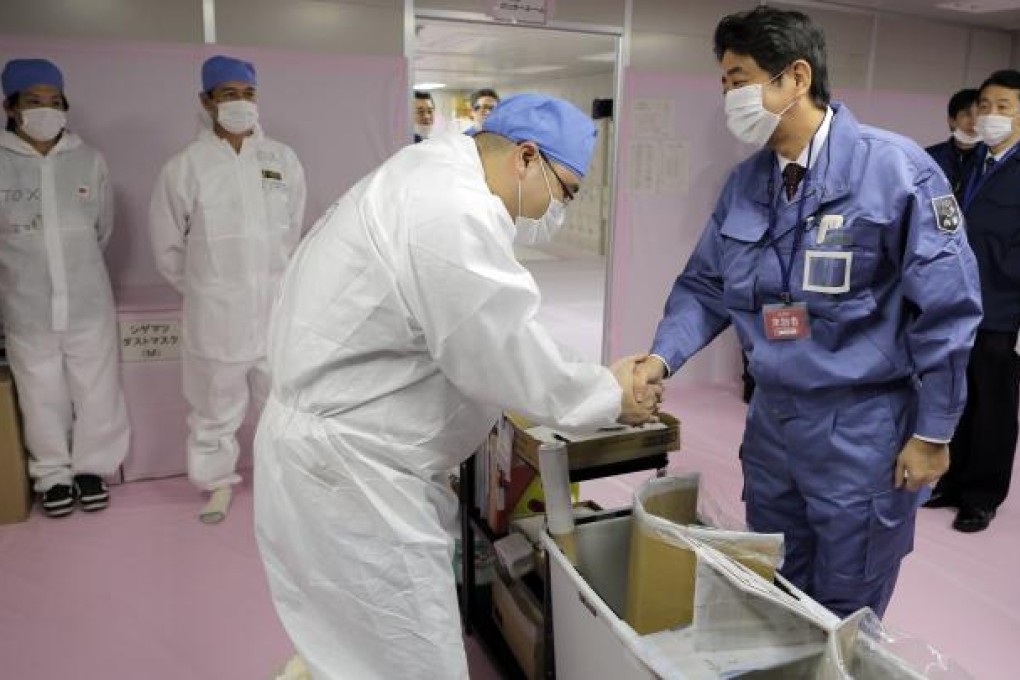 Japan's new Prime Minister Shinzo Abe greets a worker at the crippled Fukushima Dai-ichi nuclear power plant in December. Photo: AP