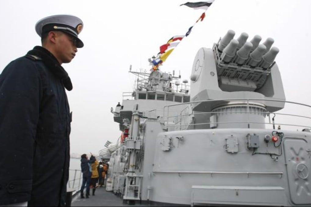 A member of China's People Liberation Army (PLA) stands at guard on the missile destroyer 'Qingdao'. Photo: EPA