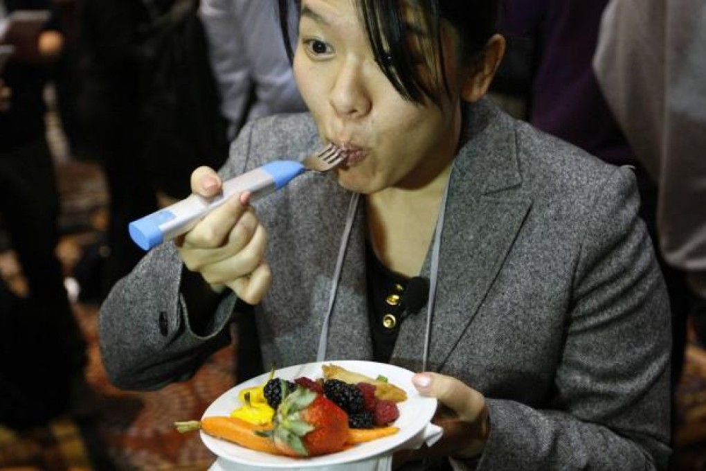 A Japanese reporter tries out the HAPIfork at a media event ahead of the Consumer Electronics Show (CES) in Las Vegas. The fork tracks the number of fork servings the user takes, and warns if the user is eating too fast. The show opens on Tuesday. Photo: Reuters