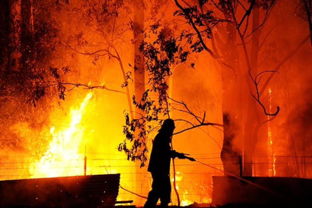 A fire fighter is almost surrounded by red hot flames as he protects a property threatened by the Dean's Gully fire, New South Wales, on Tuesday. Photo: EPA