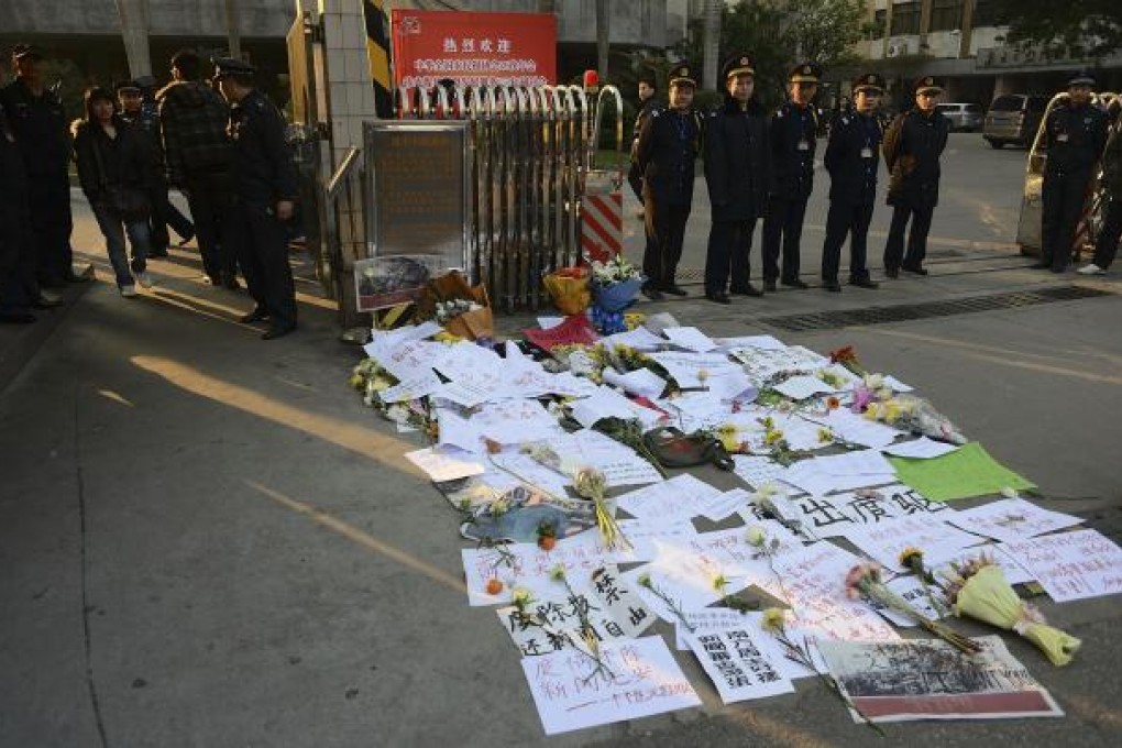Security guards stand near protest banners and flowers are laid outside the headquarters of Southern Weekly newspaper in Guangzhou, Guangdong province. Photo: AP