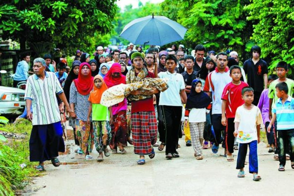 The father of 11-month-old Infami Samoh carries his daughter's body to the village burial ground after an attack on a teahouse in Narathiwat province.