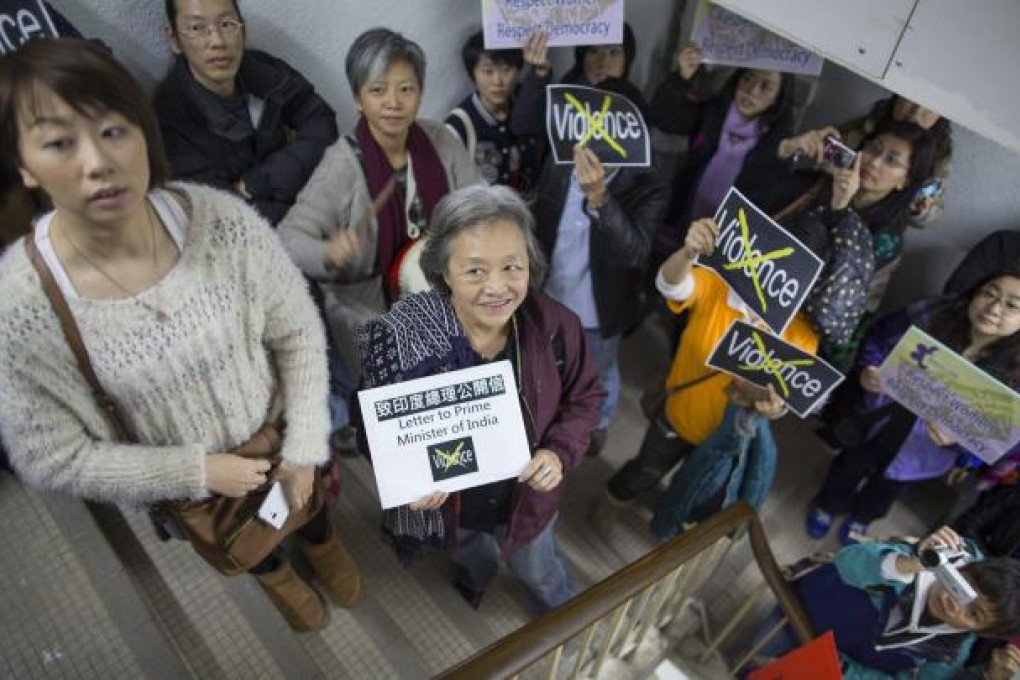 Participants hold placards and chant slogans as they take part in a march against violence towards women in a staircase leading to the India consulate in Hong Kong. Photo: EPA