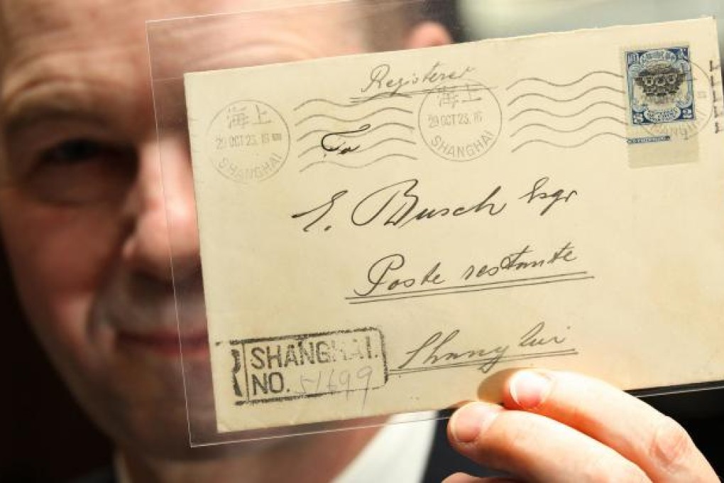 A specialist at Spink China holds up a cover bearing a rare stamp depicting the Peking Hall of Classics, inverted by mistake. Thanks to this printing error, the item is expected to fetch up to HK$6 million when it is offered for sale at Spink's auction of Chinese, Hong Kong and Burmese coins and stamps in Wan Chai this weekend. Photo: Dickson Lee