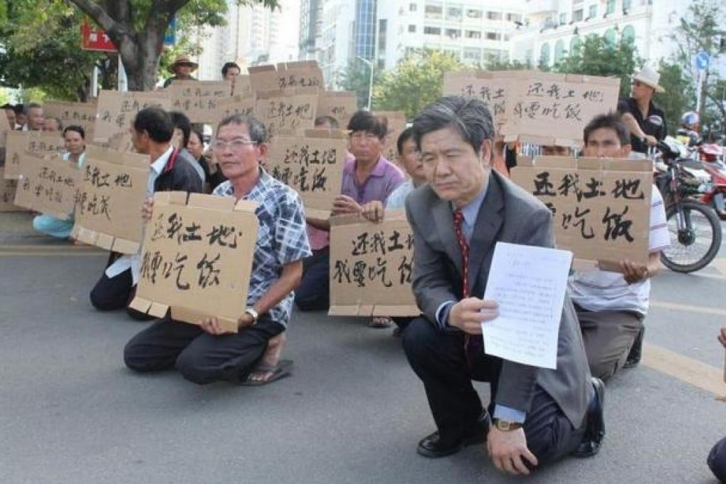 Farmers kneel and hold up placards reading "return our land, we need food" outside Sanya government offices to protest a 1991 land grab. Photo: SCMP Pictures