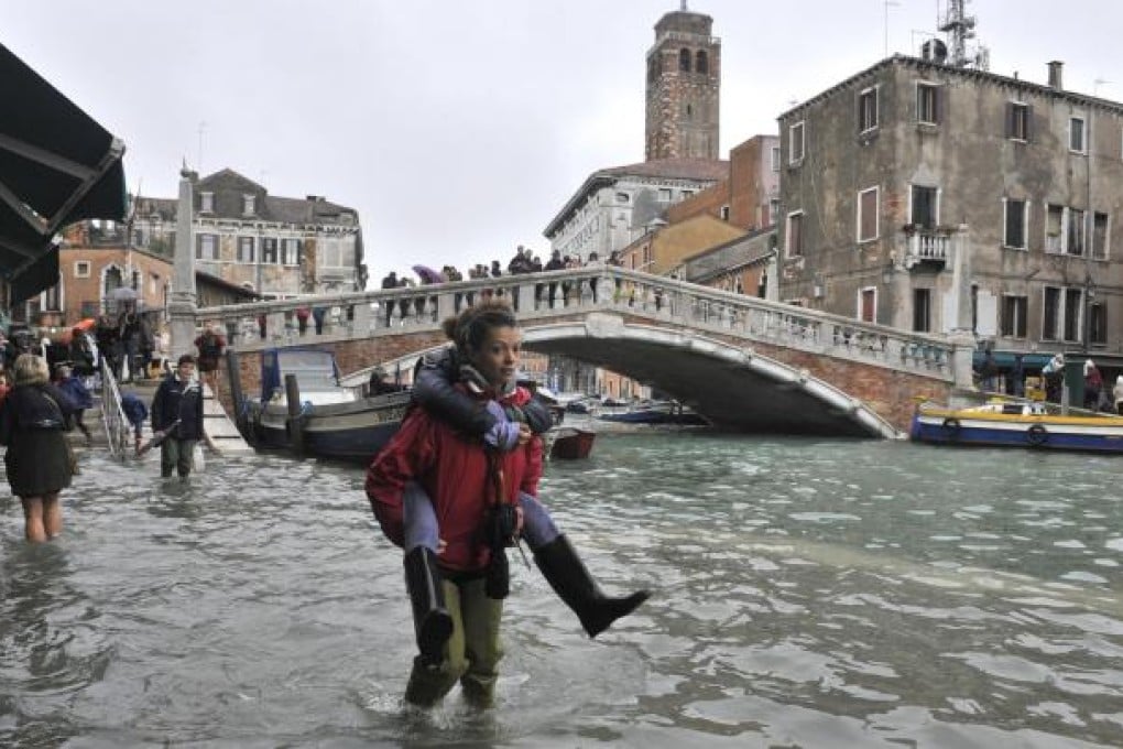 People walk in high water near the Ponte delle Guglie in Venice, Italy. Joseph Stiglitz says global warming is one of the long-term problems our world is facing. Photo: AP