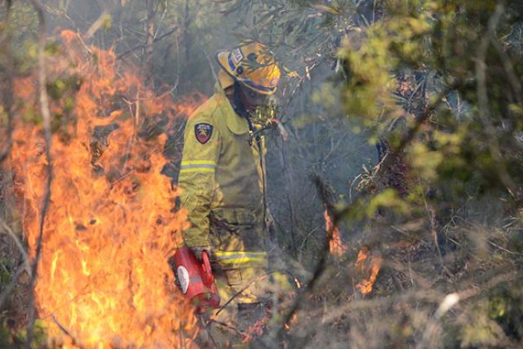 A Queensland Fire and Rescue crew member gets in close to douse flames on Bribie Island, north of Brisbane, on Wednesday. Photo: EPA