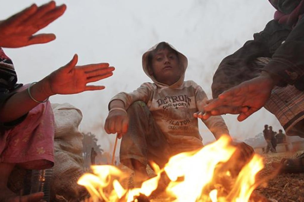 People warm themselves by a fire in Dhaka on Thursday as Bangladesh recorded its lowest temperature in 45 years. Photo: Reuters