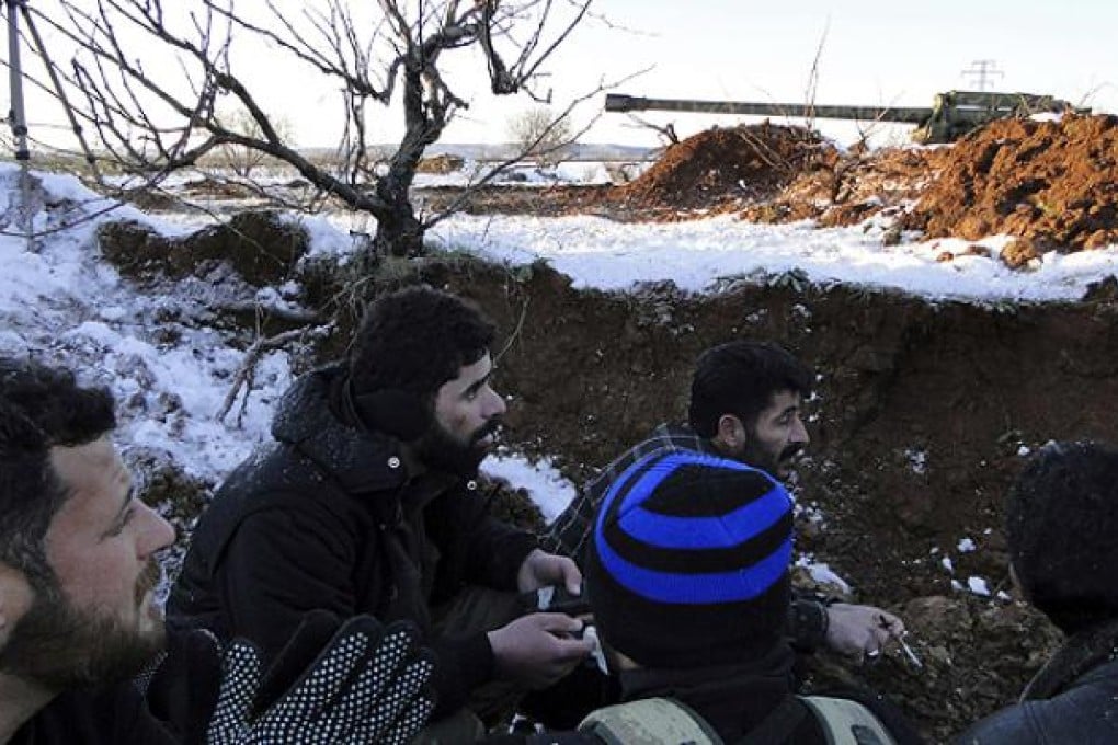 Members of the Free Syrian Army sit in a trench during the liberation of Menagh military airport. Photo: Reuters