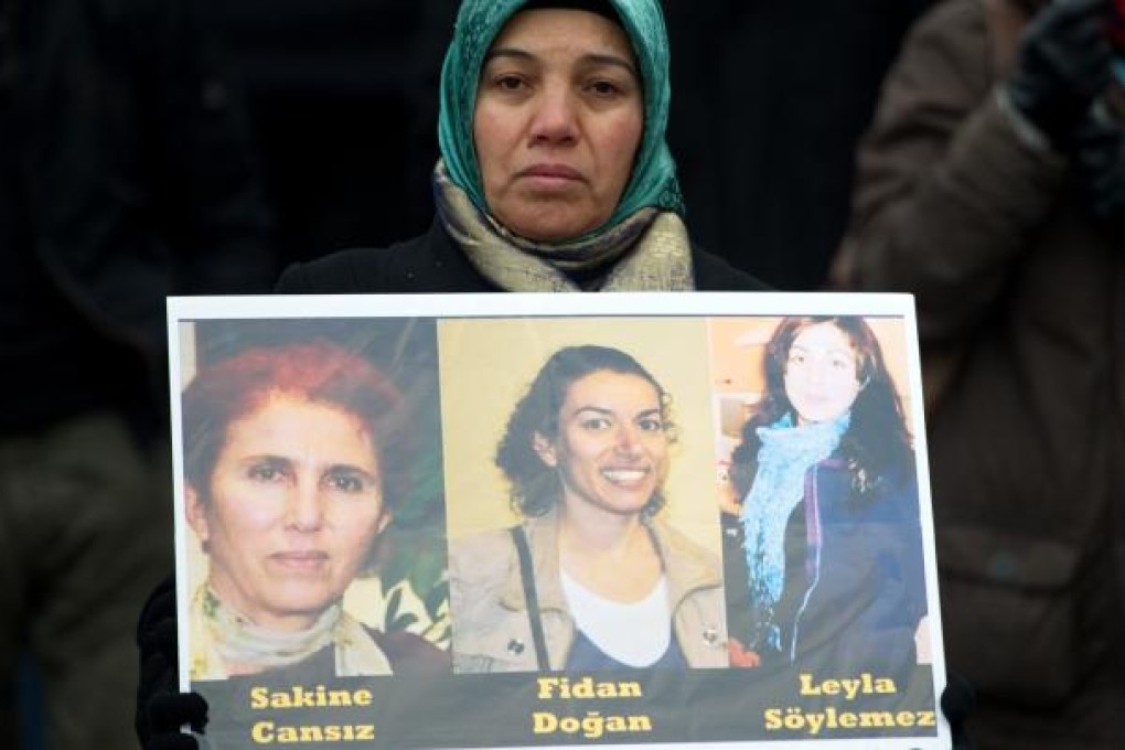 A woman hold pictures of three murdered female Kurdish activists during a demonstration of Kurdish organizations in Hamburg, northern Germany. Photo: AP