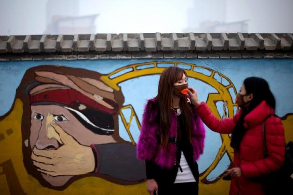 Friends adjust their masks against the choking pollution outside an amusement park on a hazy day yesterday in Beijing. Photo: AP