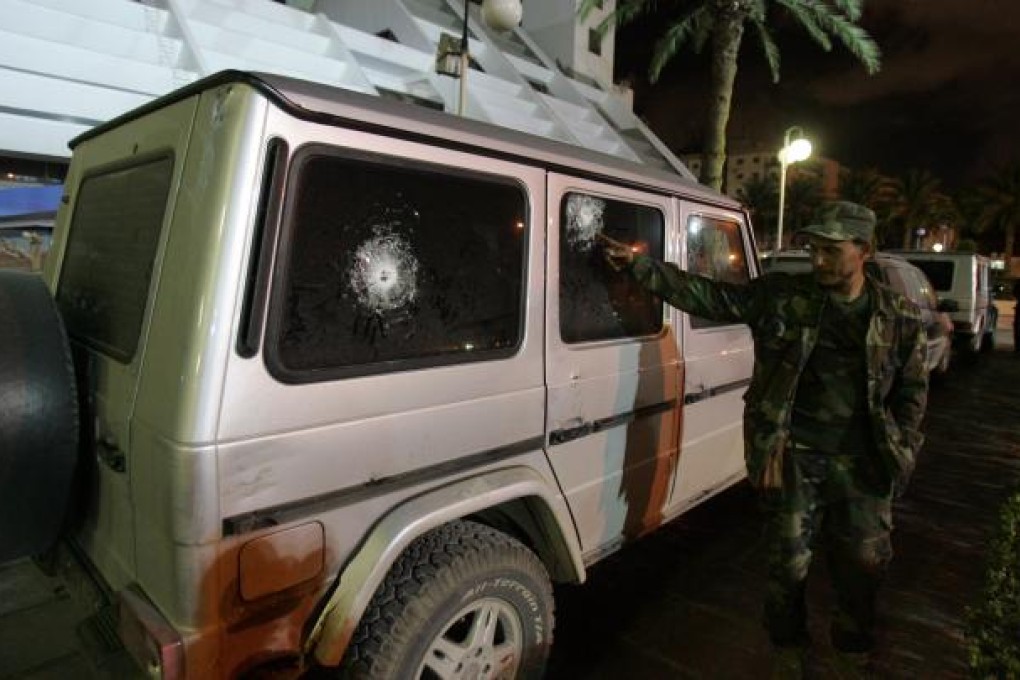 A security guard points to the bullet impacts on the bulletproof vehicle of Italy's consul to Benghazi. Photo: AFP