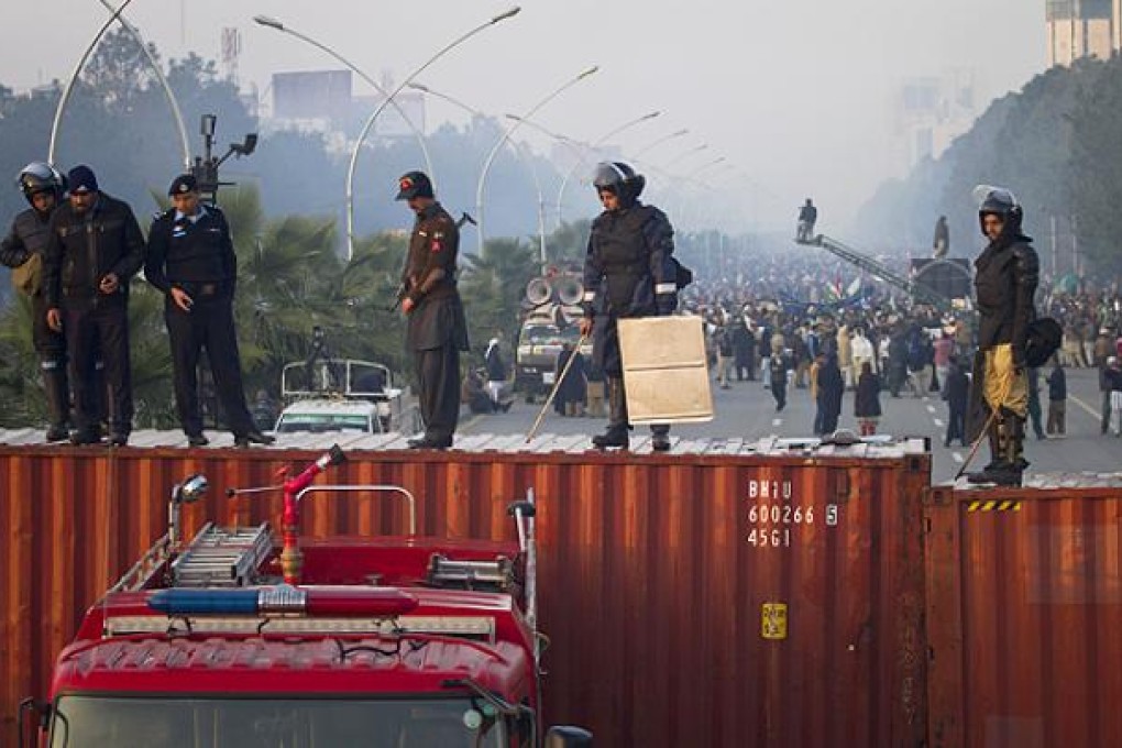 Pakistani police officers stand guard on a barricade made shipping containers in Islamabad on Tuesday. Photo: AP