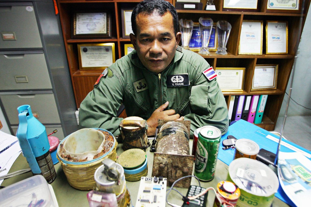 Major Chane Warongkhapaisit, head of the Narathiwat Police bomb squad, displays home-made bombs his team has defused, including a landmine built inside a sardine can (below right).