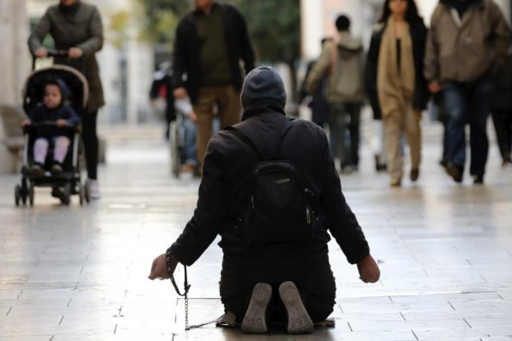 A man begs outside at a market in Valencia, eastern Spain. The World Bank has warned that a slow recovery in developed nations is acting as a brake on the global economy. Photo: EPA