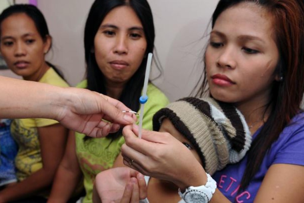 Young mothers, who can now get  free birth control, inspect an intrauterine device at the Likhaan Centre for Women’s Health in Baseco, a massive slum in Manila. Photo: AFP