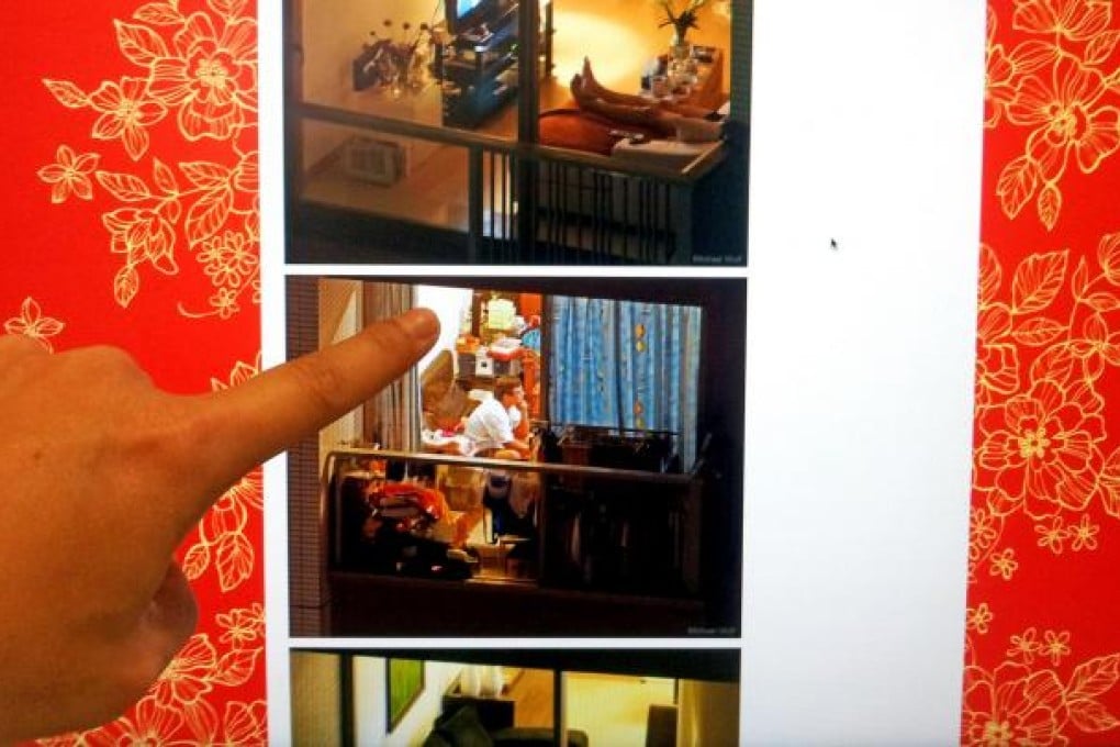 In a posed picture, a person points to a website that features examples from photographer Michael Wolf’s “Window Watching” series.
