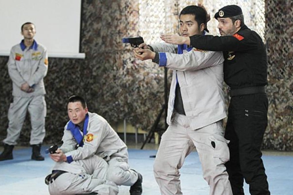 An instructor gestures as students hold rubber guns during a bodyguard training session in Beijing on Wednesday. Photo: Reuters