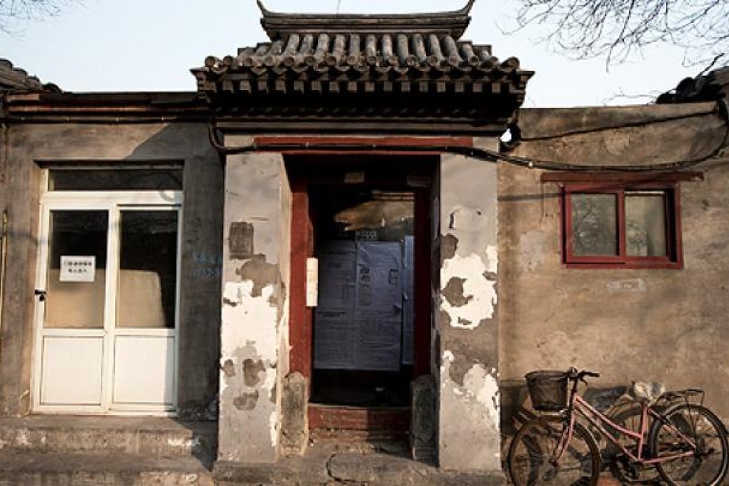 A bicycle is parked outside a Hutong home with a demolition notice seen behind the entrance wall near the historical Drum and Bell Tower in Beijing. Photo: AP