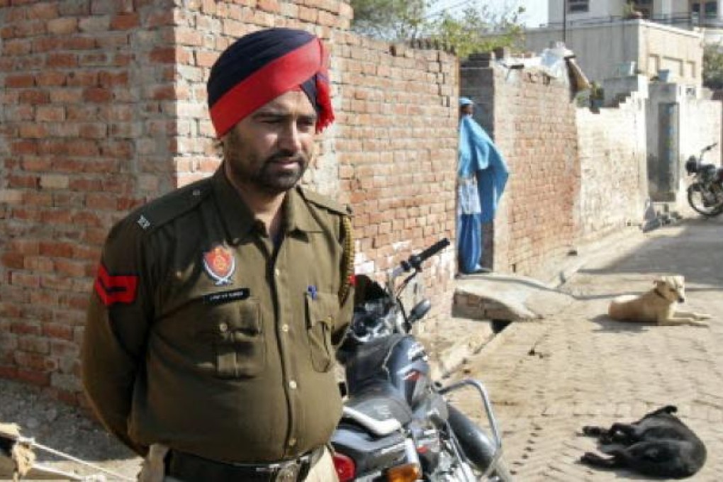 A policeman stands guard as a woman covers her face near the house of a gang rape victim at village Badshahpur in the northern Indian state of Punjab. Photo: Reuters